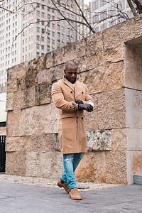 man walking beside brown wall during daytime thumbnail