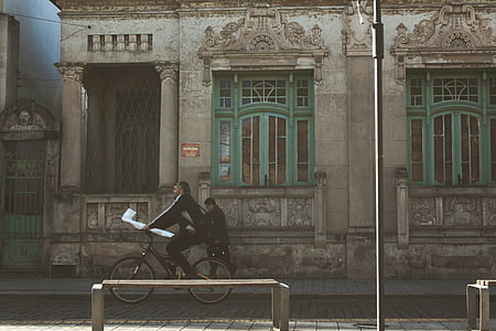 man biking near person walking on isle beside concrete building thumbnail