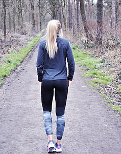 woman walking in pathway between bare trees thumbnail