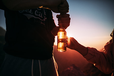 man holding glass bottle near woman thumbnail