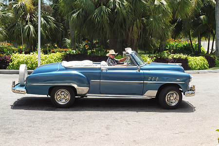 man riding blue convertible coupe near palm tree thumbnail