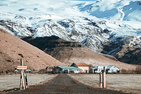 brown and green house near snow covered rocky mountain during daytime photo thumbnail