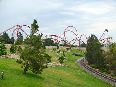 green grass open field across red roller coaster amusement park at daytime thumbnail