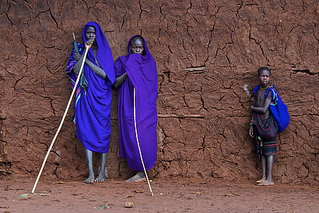 three person standing beside brown wall thumbnail