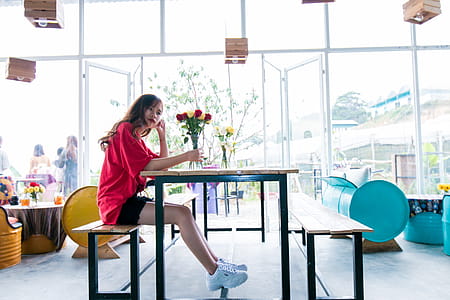 Woman Wearing Red Top Sitting in Brown Chair thumbnail