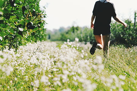woman wearing black top and black short shorts walking on green grass field thumbnail