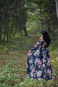woman in blue, pink, and green floral dress surrounded by trees thumbnail