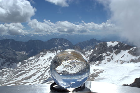 water globe on gray surface in front of mountain peak thumbnail