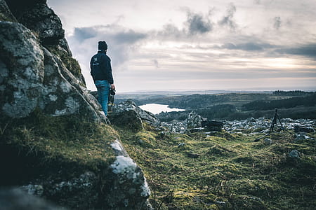 man standing on grass covered mountain thumbnail