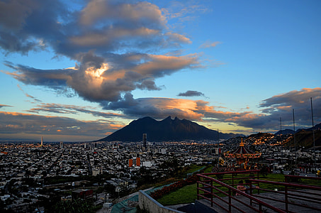 aerial photography of buildings leading to mountain under thick clouds and blue sky thumbnail