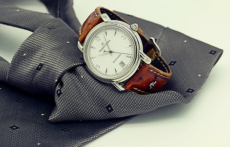 round silver-colored bezel analog watch on top of gray necktie thumbnail