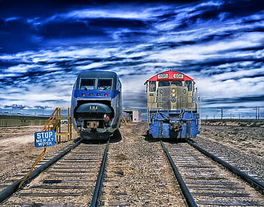 two blue, gray, and brown locomotives on black railroads taken at daytime thumbnail