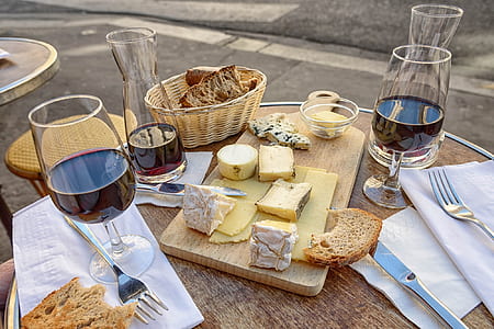 clear short-stemmed wine glasses, sliced breads, brown wooden chopping board, and brown wicker basket on brown wooden table thumbnail