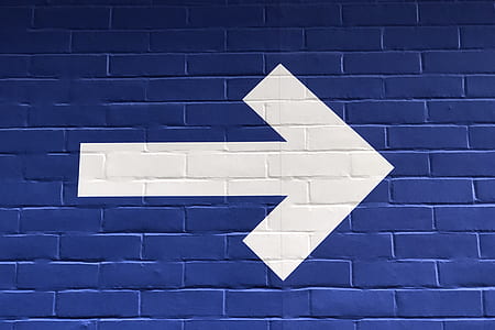 blue wall with white painted arrow pointing on right direction thumbnail
