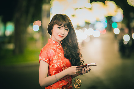 woman in orange floral traditional dress holding book thumbnail