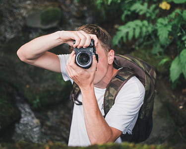man using black DSLR camera while capturing photo thumbnail