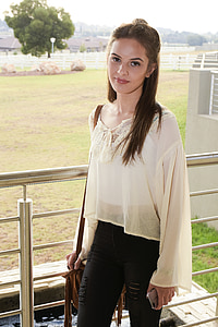 woman in white long-sleeved shirt standing beside gray handrail thumbnail
