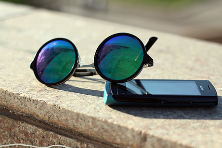 black framed hippie sunglasses beside black Android smartphone on top gray concrete surface thumbnail