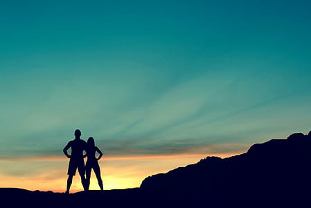 Couple standing together on a hilltop with sunset in tha background. thumbnail