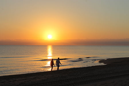 two persons walking at the beach during golden hour thumbnail