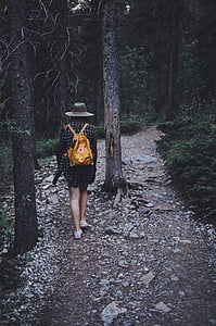 woman walking between green plants and trees thumbnail