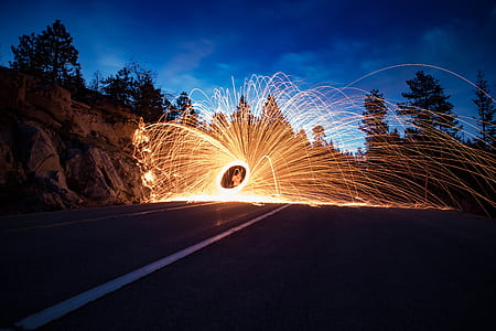 steel wool photography of person near rock formation under blue sky during nighttime thumbnail