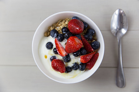 Bowl of yogurt, strawberries, blueberries and granola breakfast cereal with spoon thumbnail