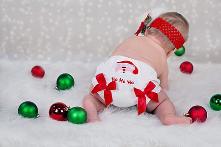 baby in white diaper playing green and maroon baubles thumbnail