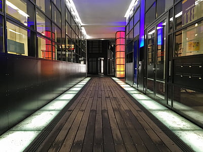 brown parquet floor hallway between glass windows inside building during night time thumbnail