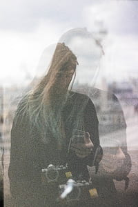 woman holding phone and wearing DSLR camera thumbnail