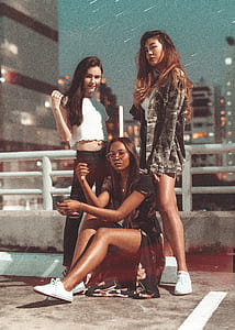 three woman standing and sitting near barricade thumbnail