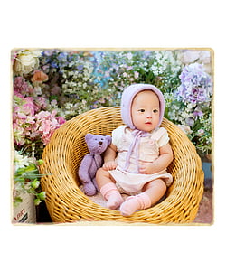 baby sitting on brown rattan chair beside purple plush toy thumbnail