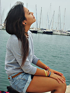woman wearing blue denim short shorts sitting beside body of water thumbnail