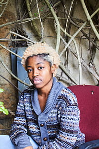 Woman Wearing Blue, White, and Brown Fair-isle Button-up Cardigan Sitting on Red Chair thumbnail