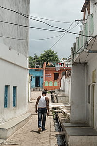 man walking on pavement beside concrete building at daytime thumbnail