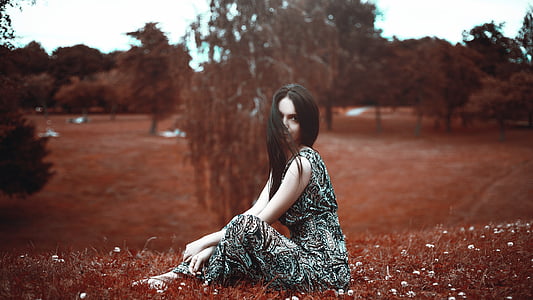 woman wearing black and white sleeveless dress sitting on grass thumbnail