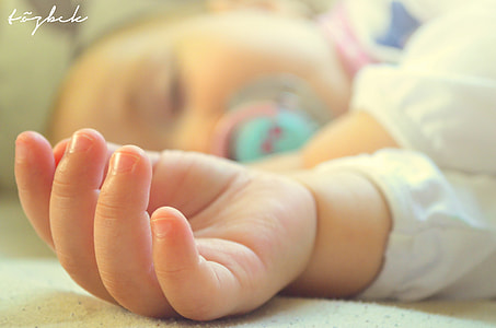 tilt shift photography of baby's hand laying thumbnail