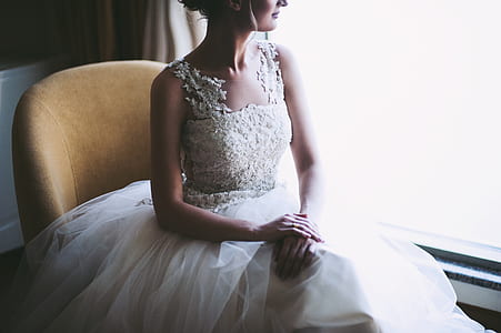 woman wearing white lace square-neck sleeveless wedding dress sitting near the window thumbnail