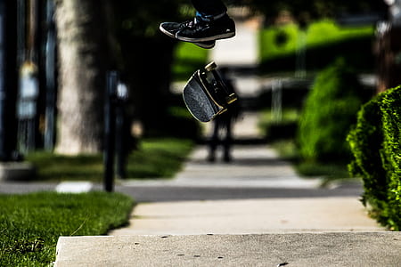 person doing skateboard stunt in mid-air near green grasses and leafed plants during daytime thumbnail