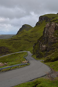 road beside hills under dark clouds thumbnail