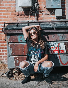 woman sitting beside brown trash bin thumbnail