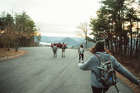 people walking on asphalt road towards red SUV thumbnail