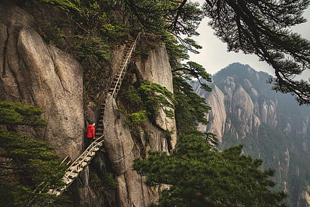 man walking on stairs on mountain side during daytime thumbnail