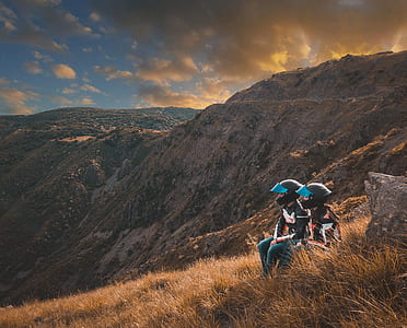 two person's sitting on grass overlooking mountains during golden hour thumbnail