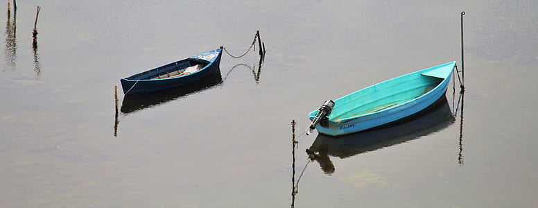 two blue and green canoe boat on body of water thumbnail