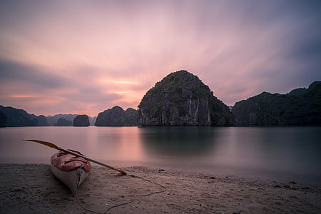 canoe on shoreline with islet landscape photograph thumbnail
