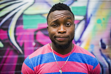 man wearing pink and blue stripe v-neck shirt with graffiti background thumbnail