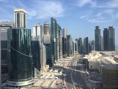 vehicles on concrete road between city buildings during daytime thumbnail