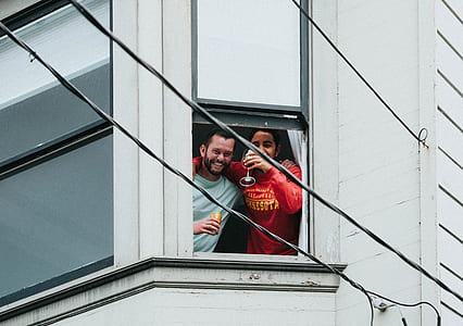 man and woman holding wine glass standing in front of open window thumbnail