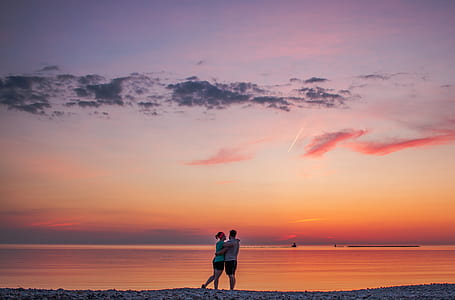 couple stands near sea and hugs each other during sunset thumbnail